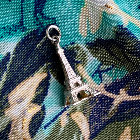 Silver Eiffel Tower charm on a fabric background