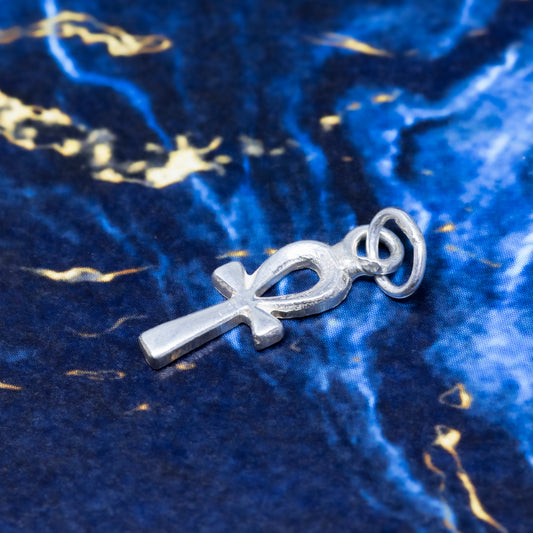 A silver ankh pendant on a blue background.