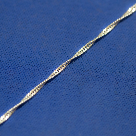 A close-up of a silver twisted curb link chain on a blue background.