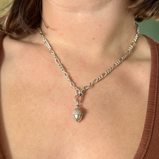 Silver necklace with acorn pendant worn by a person