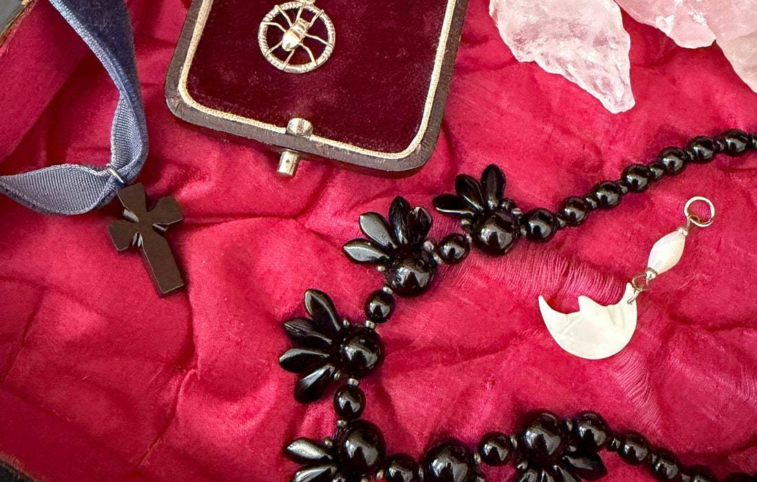 A collection of silver and jet jewellery, on a pink silk background.