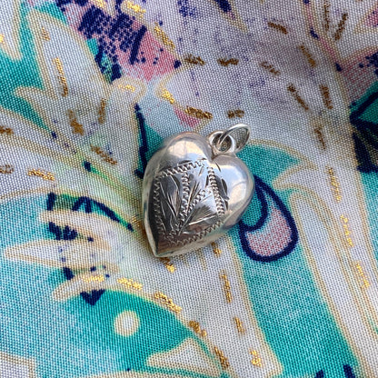 Silver heart-shaped pendant on a colorful fabric background