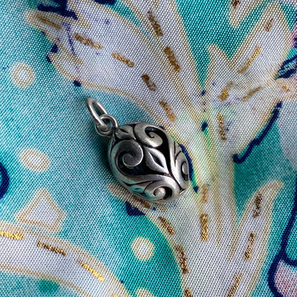 Silver pendant on a fabric background with blue and gold patterns