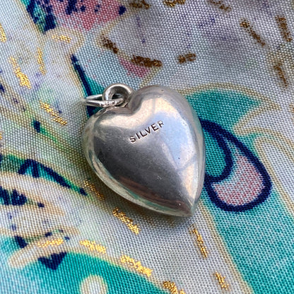 Silver heart-shaped pendant on a colorful fabric background