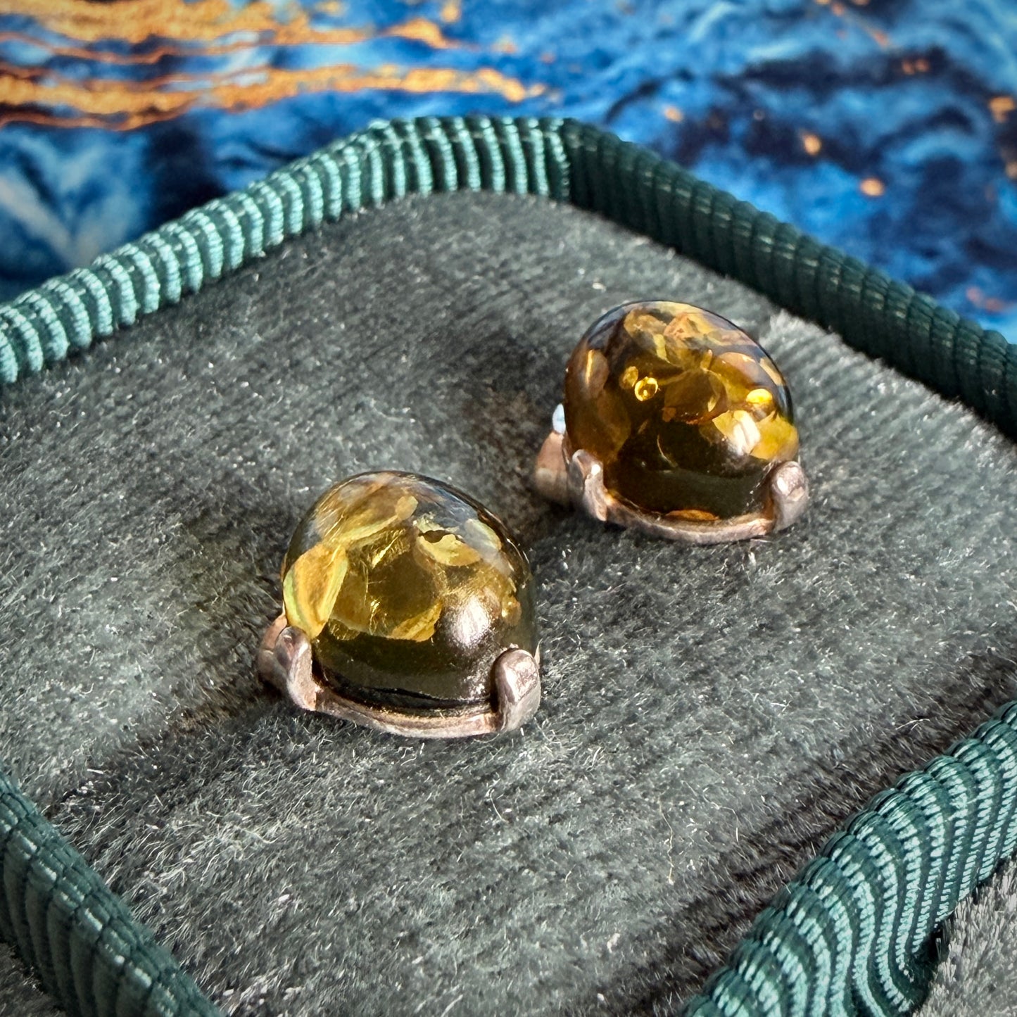 Side profile of a pair of amber stud earrings, in four claw settings.